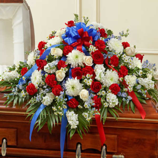 Red and white floral casket spray with blue and red ribbons