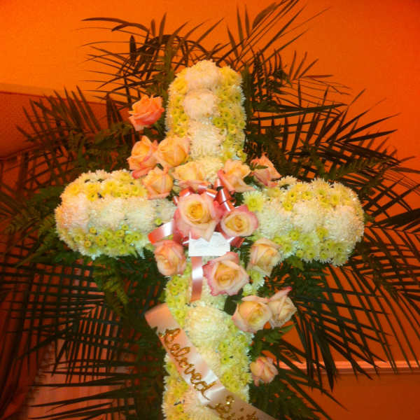 Cross-shaped floral tribute with white chrysanthemums and peach roses