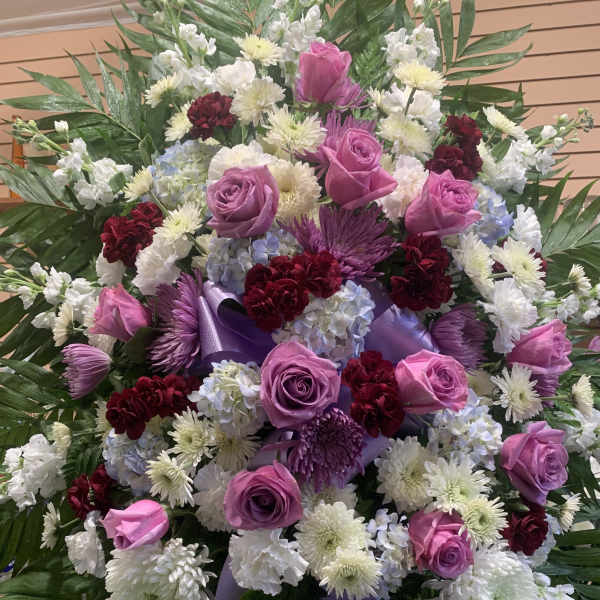 Large standing spray of pink roses, white chrysanthemums, and purple ribbon