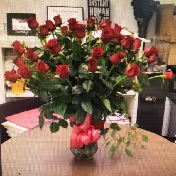 Bouquet of red roses in a glass vase with a pink ribbon