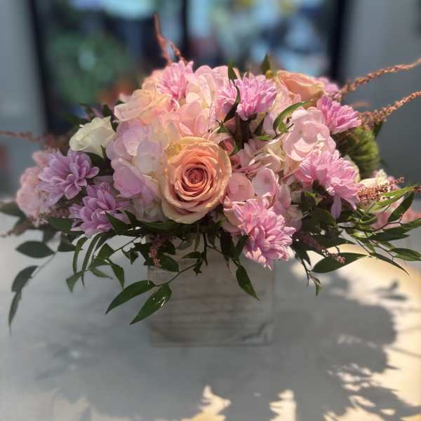 Pink and peach floral arrangement in a square vase
