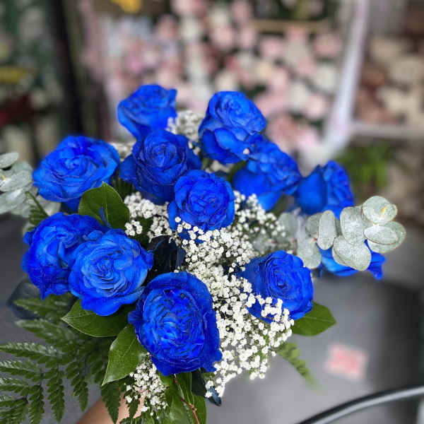 Bouquet of vivid blue roses with white filler flowers and greenery