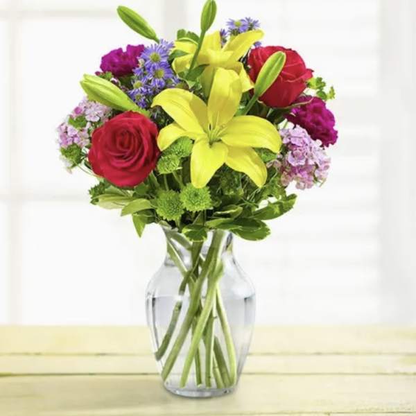 Bouquet of red roses and yellow lilies in a clear glass vase