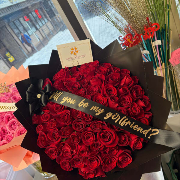 Large bouquet of red roses wrapped in black paper with a ribbon