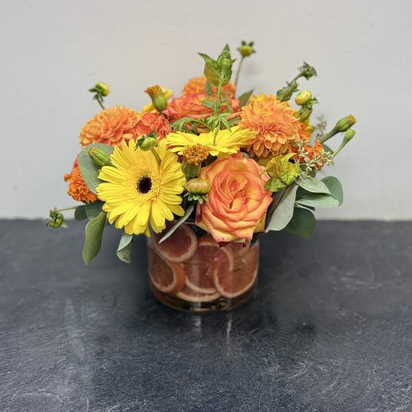 Orange and yellow flower arrangement in a glass vase