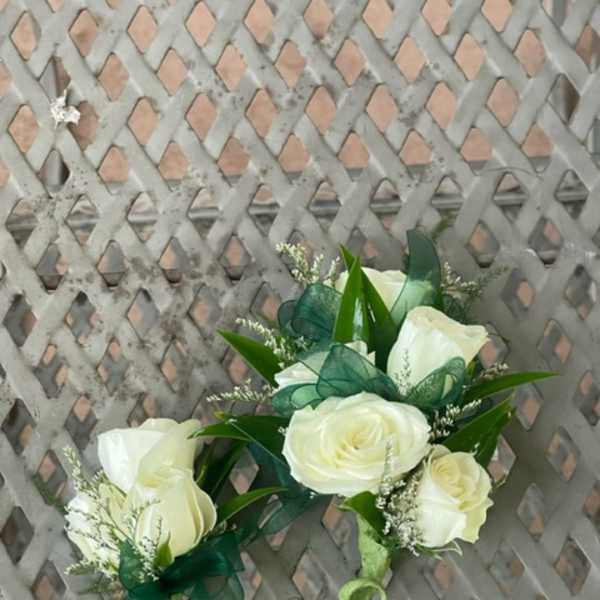 White rose corsages with green ribbon accents