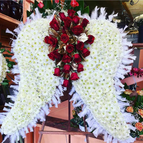 Large heart-shaped floral tribute with white flowers and red roses on an easel
