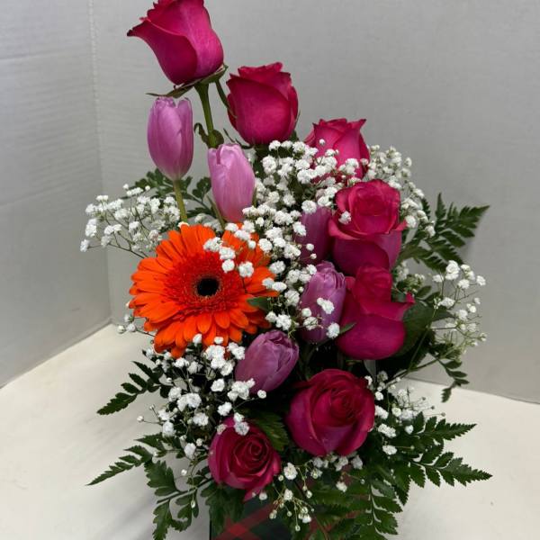 Pink roses and tulips with an orange gerbera daisy in a gift box