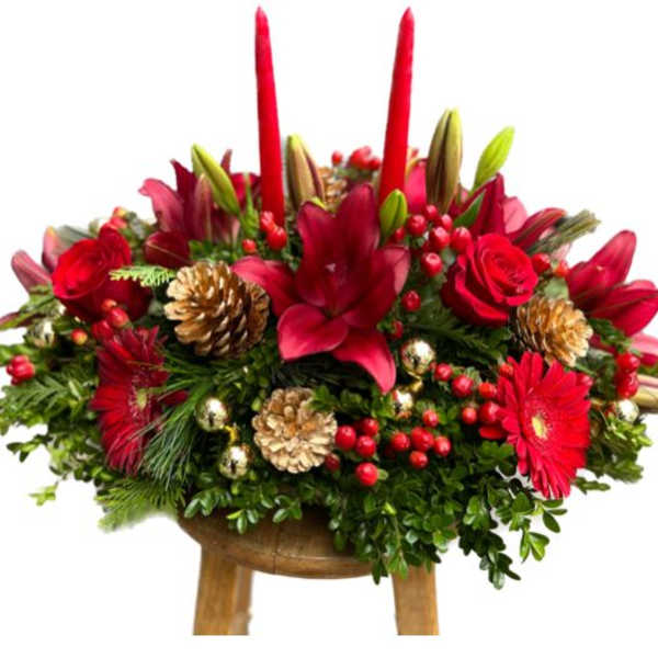 Red floral centerpiece with pinecones and candles on a wooden stand