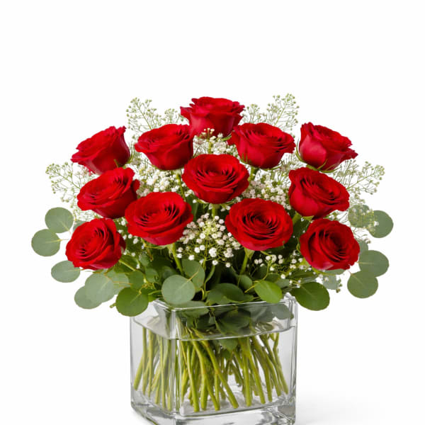 Red roses arranged in a clear square glass vase