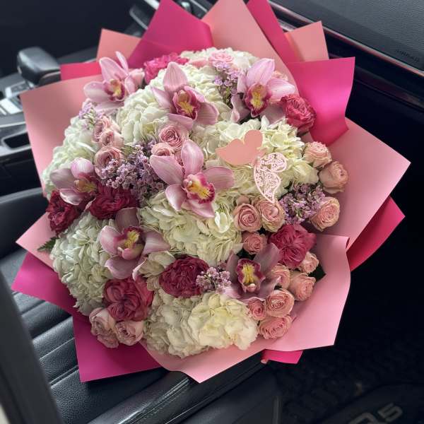 Pink and white bouquet with orchids and roses wrapped in pink paper