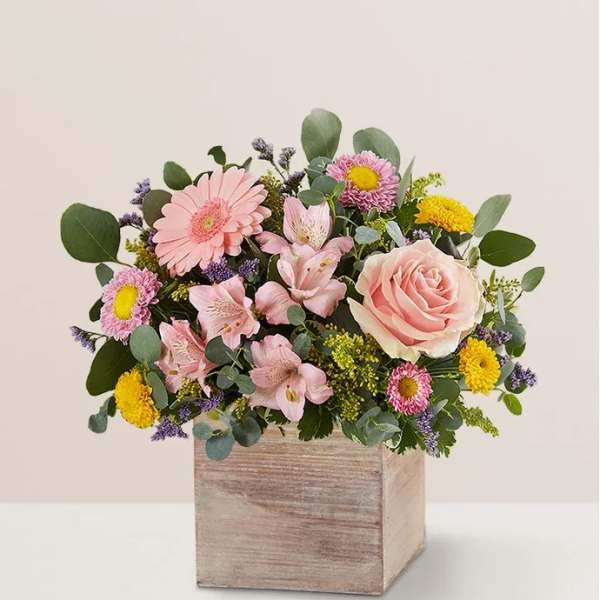 Pink and yellow mixed flower arrangement in a wooden box