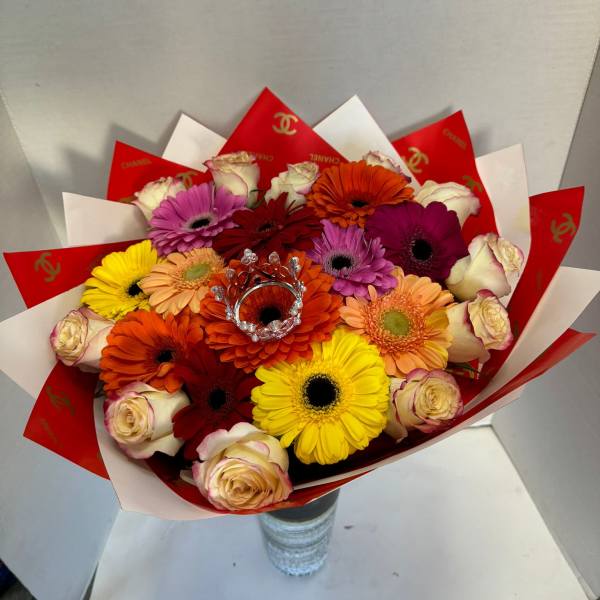 Colorful bouquet of gerbera daisies and roses wrapped in red and white paper