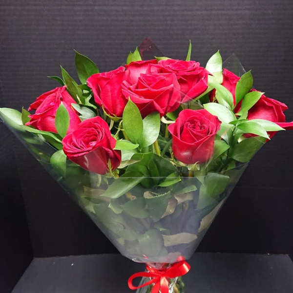Bouquet of red roses wrapped in clear plastic with a red ribbon