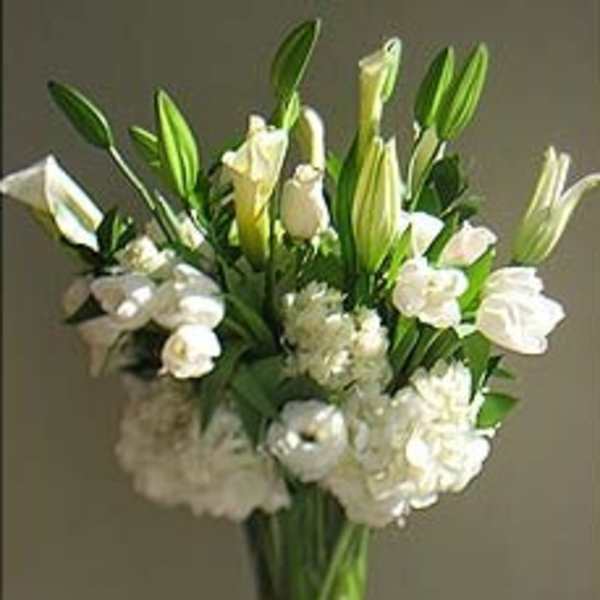 White lilies and roses arranged in a clear glass vase
