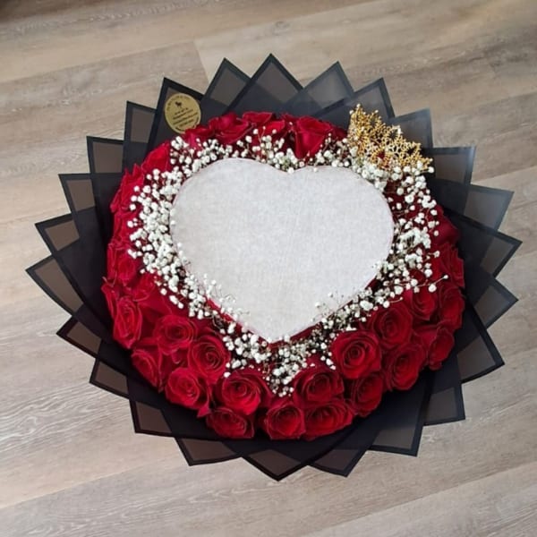 Heart-shaped bouquet of red roses with white baby's breath and black wrapping