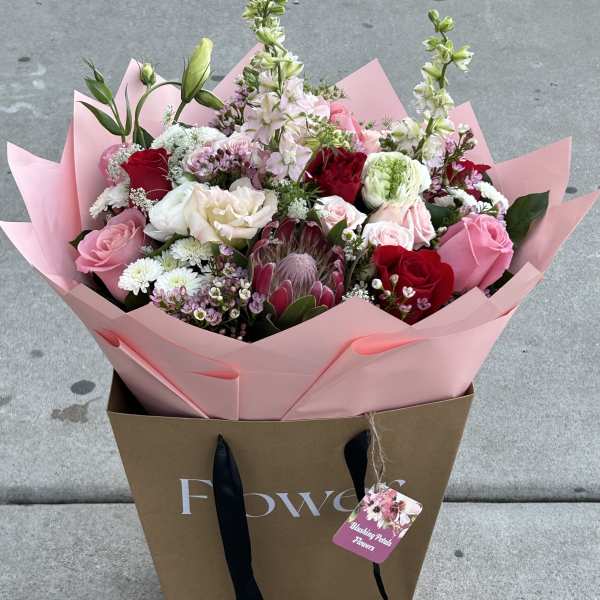 Mixed bouquet of pink, red, and white flowers in pink wrap