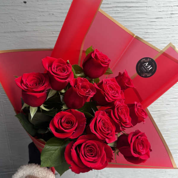 Bouquet of red roses wrapped in red paper with gold trim