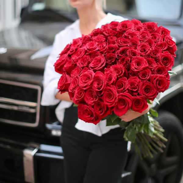 Large bouquet of red roses held in front of a person
