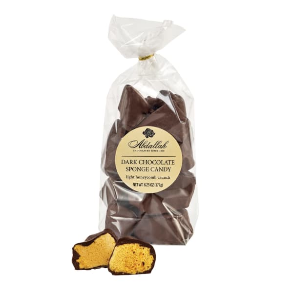 Bag of dark chocolate sponge candy with one piece cut open to show golden honeycomb center.