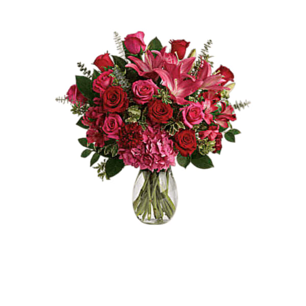 Pink and red bouquet of roses and lilies in a clear glass vase