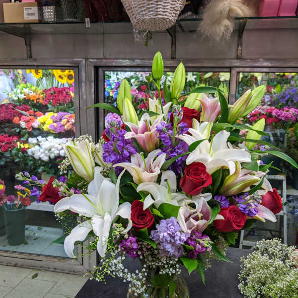 Large bouquet of lilies, roses, and purple flowers in a glass vase