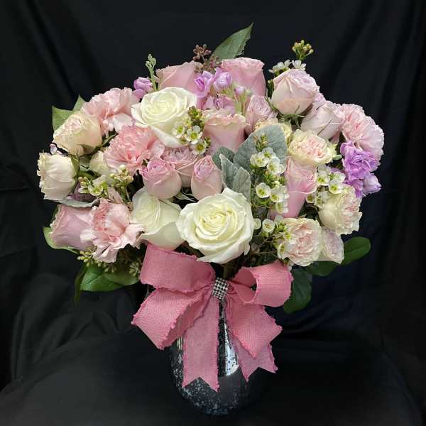 Pink and white rose bouquet in a black vase with a pink ribbon