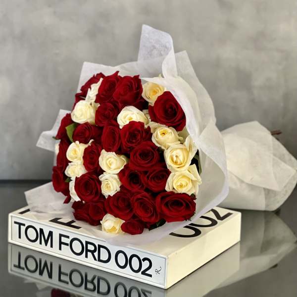 Bouquet of red and cream roses wrapped in white paper
