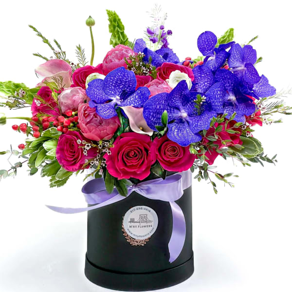 Bright mixed bouquet in a black hatbox with a lavender ribbon
