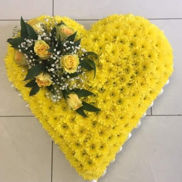 Heart-shaped yellow floral arrangement with yellow roses and dark greenery