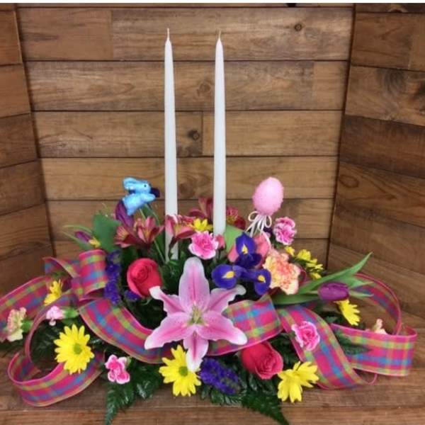 Colorful floral centerpiece with two white taper candles and a plaid ribbon