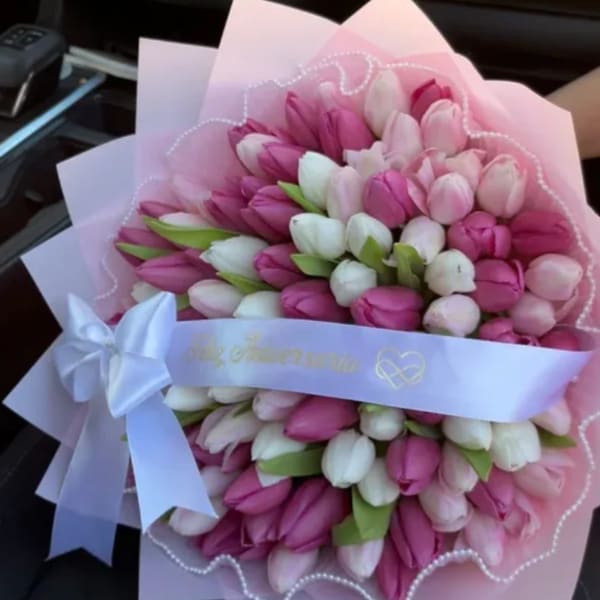 Bouquet of pink and white tulips wrapped in pale pink paper with a white ribbon