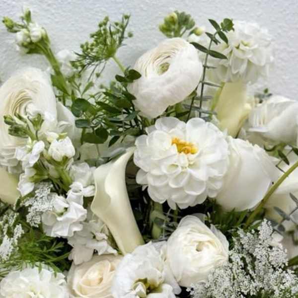 White floral arrangement with calla lilies, ranunculus, and dahlias