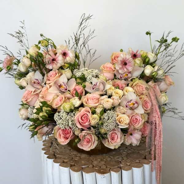 Large pastel bouquet of pink and cream roses with orchids in a basket