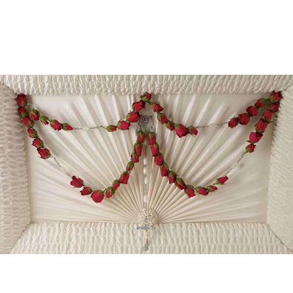 White casket with red rose garlands and a rosary cross