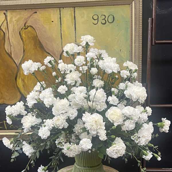 Large white carnation arrangement in a green vase