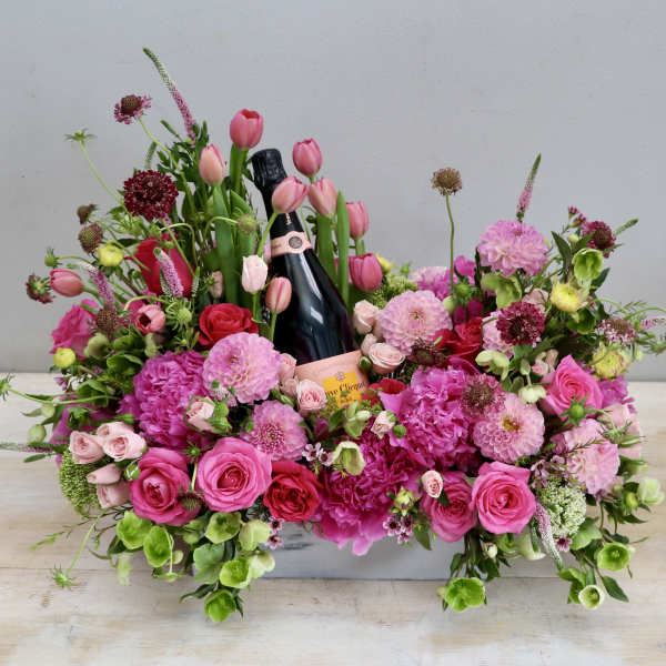 Pink floral arrangement with a champagne bottle in the center