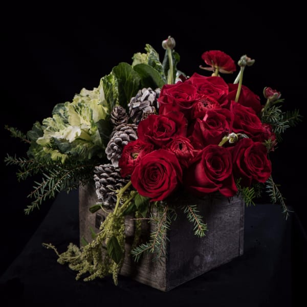 Red roses in a rustic wooden box with pinecones and greenery