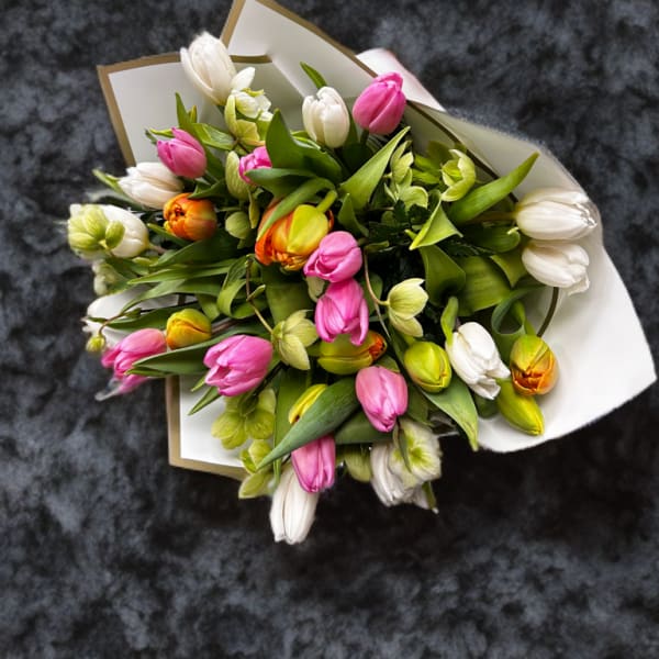 Bouquet of pink, white, and orange tulips wrapped in white paper