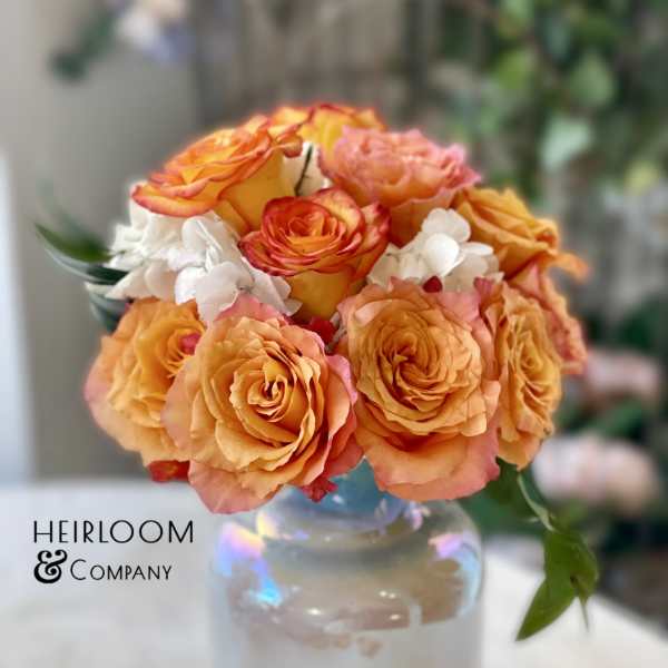Orange and pink rose bouquet in a glass vase
