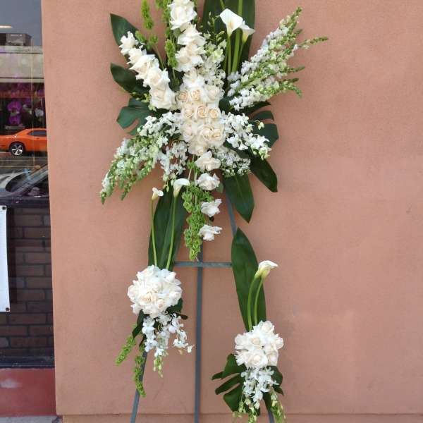 Tall white floral standing spray on a metal easel