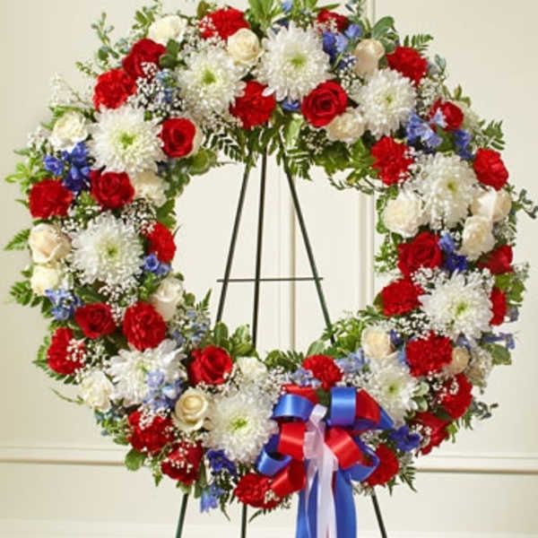 Large red, white, and blue floral wreath on an easel with ribbon