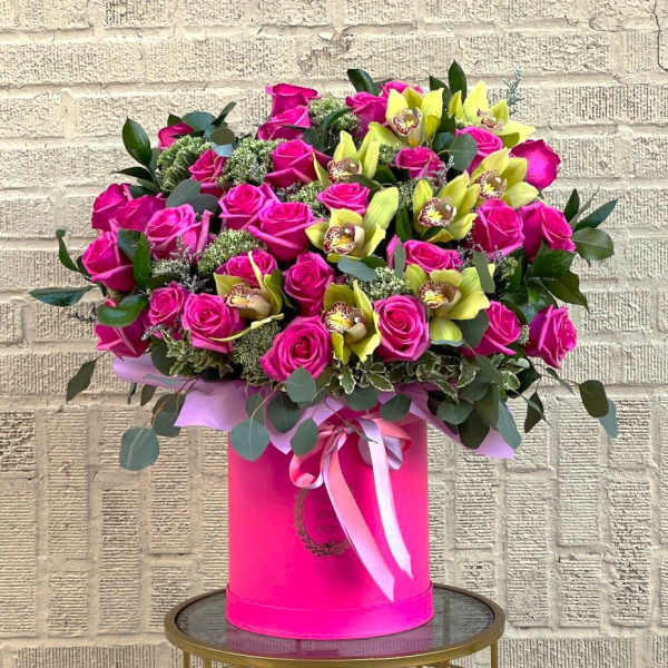 Large bouquet of pink roses and yellow orchids in a pink hat box