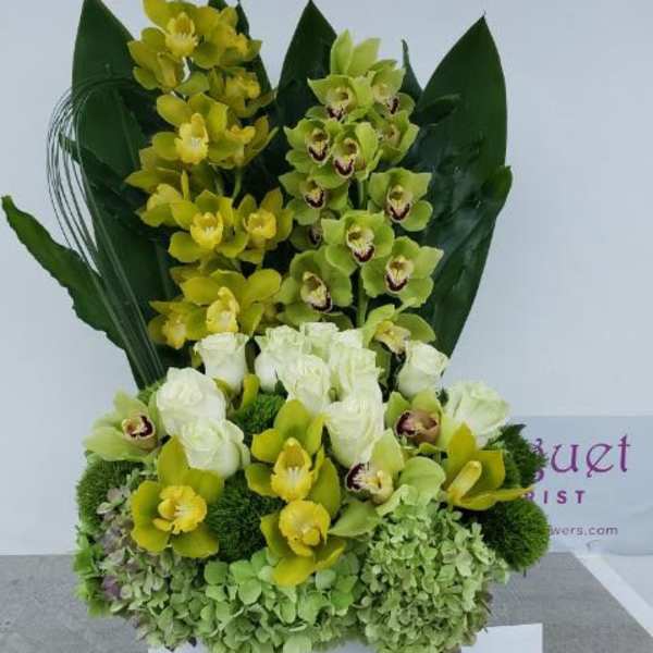 Yellow and green orchid arrangement with white roses in a box