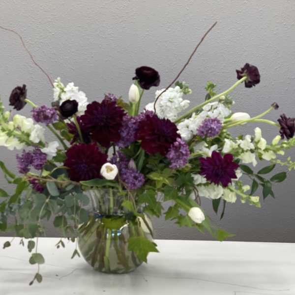 Purple and white floral arrangement in a glass vase