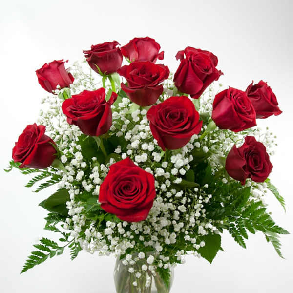 Red roses arranged in a clear glass vase with white baby's breath