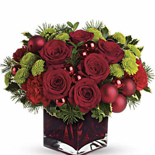 Red roses and green pom flowers in a red glass vase with ornaments