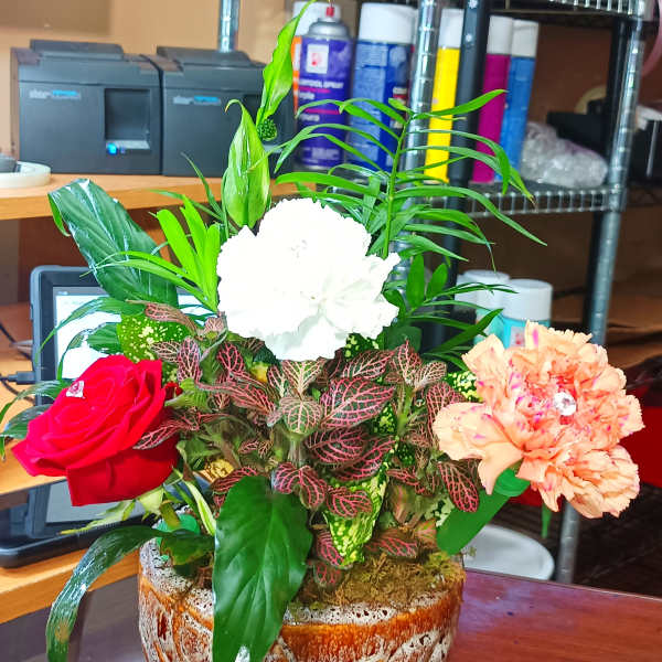 Mixed floral arrangement in a rustic ceramic pot with red, white, and peach blooms