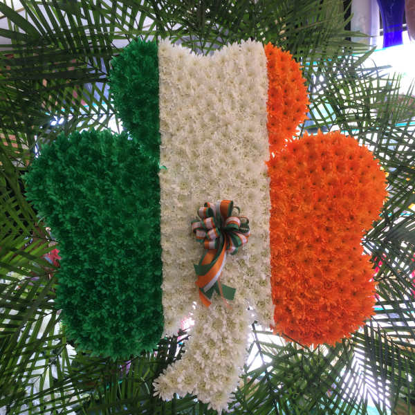 Floral tribute in green, white, and orange with a ribbon bow