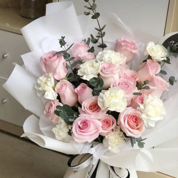 Bouquet of pink roses and white carnations wrapped in white paper